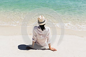 Summer lifestyle of woman wearing straw hat sitting on the beach in tropical island.