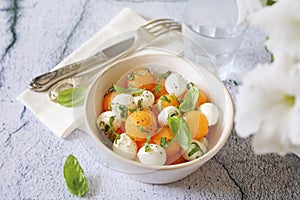 Summer light food. Mozzarella and melon salad with basil