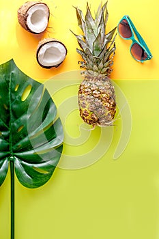 Summer mix with sun glasses, pineapple and coconut yellow background top view mockup