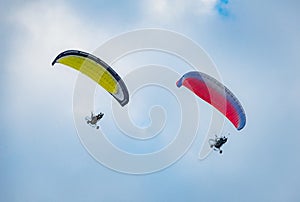 Summer mood: two pilots the paraglider on the blue sky background.
