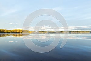 Summer morning in the forest with lake, forest reflection and mist on the water surface