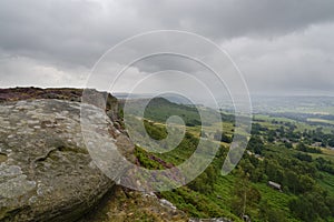 On a summer morning unseasonably dark grey skies and mist over Curbar Edge the Derbyshire Peak District