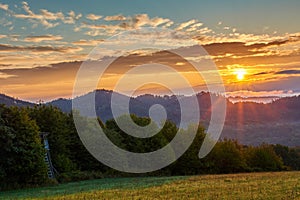 Summer mountain landscape with forest at sunrise, sunstar.