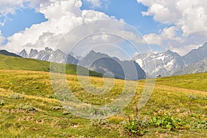 Summer mountain landscape in Svaneti region, Georgia, Asia. Snowcapped mountains in the background. Blue sky with clouds