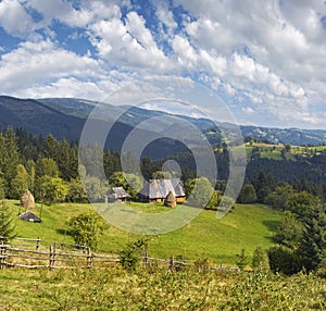 Summer mountainous green glade with small country estate