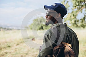 In summer in nature. Close-up young african man walking, strolling alone in forest, meadow, field. Amazing landscape