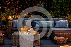 Summer night in the garden with trendy furniture, lights, lanterns and candles