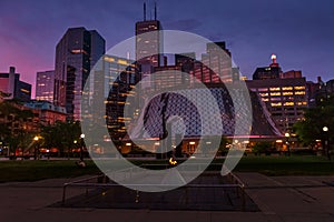 Summer night view at David Pecaut Square and skyscrapers of downtown Toronto with Eternal Flame of Hope and The Poet