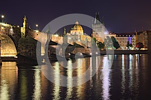 Summer night view of historical part of Prague. Vltava river, Mala Strana Bridge Tower and Charles Bridge with illumination