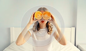 Summer, nutrition, diet and vegetarian concept. Happy healthy cheerful young woman covering her eyes with slices of orange fruits