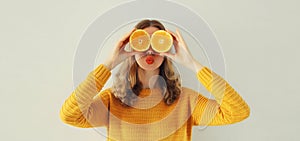 Summer, nutrition, diet and vegetarian concept. Happy healthy cheerful young woman covering her eyes with slices of orange fruits