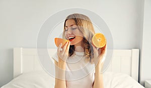 Summer, nutrition, diet and vegetarian concept. Happy healthy cheerful young woman with slices of orange fruits in white room at