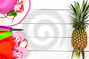 Summer objects of pineapple,lady hat,Flip flops umbrella with sunglasses summer accessory on white wooden background