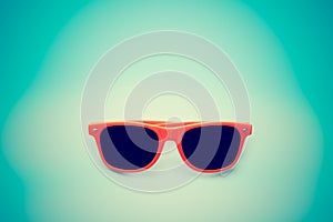 Summer orange sunglasses isolated in vignetting blue background. Minimal concept image for sun protection photo
