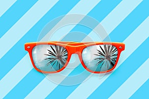 Summer orange sunglasses with palm trees reflections isolated in blue background with diagonal stripes