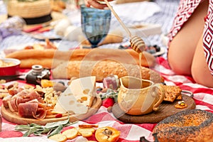 Summer outdoor picnic. Woman hold the wooden honey spoon, honey drips from it to pot. Instagram content