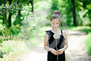 Summer outdoor portrait of a romantic girl with a big fluffy dandelion. the child holds a dry dandelion in his hands