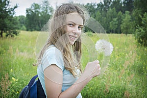 Summer outdoor portrait of a romantic girl with a big fluffy dandelion. the child holds a dry dandelion in his hands