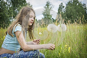 Summer outdoor portrait of a romantic girl with a big fluffy dandelion. the child holds a dry dandelion in his hands