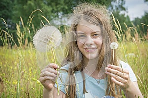 Summer outdoor portrait of a romantic girl with a big fluffy dandelion. the child holds a dry dandelion in his hands