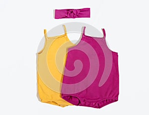 Summer outfit. Baby vest bodysuit yellow and pink color with head accessories. Top view, flat lay on white.