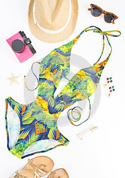 Summer outfit, beach outfit, summer stuff. Exotic pattern swimsuit, retro sunglasses, gold sandals, pink retro camera