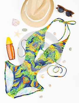 Summer outfit, beach outfit, summer stuff. Exotic pattern swimsuit, retro sunglasses and straw hat. Flat lay, top view.