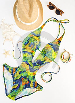 Summer outfit, beach outfit, summer stuff. Exotic pattern swimsuit, wood bracelet, retro sunglasses and straw hat. Flat