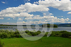 Summer partially cloudy landscape on Orava river dam, northern Slovakia. Lawn with football goalmouth and shoreline bushes.