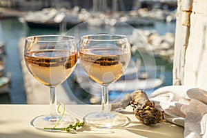 Summer party with cold rose wine in glass served on outdoor terrace in sunlights with view on old fisherman`s harbour with