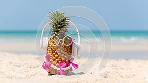 Summer in the party.  Hipster Pineapple Fashion in sunglass and listen music on the sand beach beautiful blue sky background