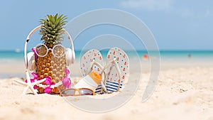 Summer in the party. Hipster Pineapple Fashion in sunglass and listen music with sunblock and sandal on the sand beach