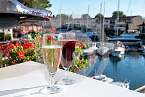 Summer party with kir royal cocktail, pouring of French brut champagne sparkling wine and cold creme cassis in glasses in yacht