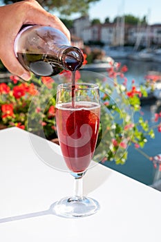 Summer party with kir royal cocktail, pouring of French brut champagne sparkling wine and cold creme cassis in glasses in yacht