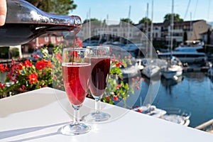 Summer party with kir royal cocktail, pouring of French brut champagne sparkling wine and cold creme cassis in glasses in yacht