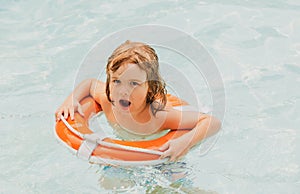 Summer party in pool. Happy kid in swimmingpool. Boy having fun at aquapark. Child with swimming ring.