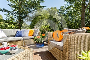 Summer patio with rattan furniture and guitar