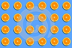 Summer pattern of orange slices on blue background. Top view of cross section of citrus fruit. Flat lay composition