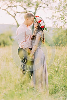 Summer photo of beautiful young couple hugging face-to-face in the garden