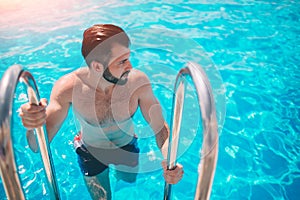 Summer photo of muscular smiling man in swimming pool. Happy male model in water on summer vacations