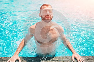 Summer photo of muscular smiling man in swimming pool. Happy male model in water on summer vacations