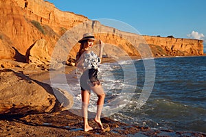 Summer photo of Sexy brunette girl with hat in fashion casual outfit enjpying on the beach at sunset. Freedom summertime vacation