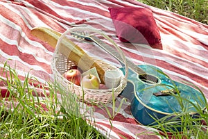 Summer picnic basket with apples and guitar lie on  plaid with pillows heat