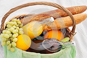 Summer picnic in the meadow on the green grass. Fruit basket, juice and bottled wine, watermelon, strawberries in a