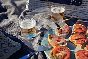 Summer picnic in nature with tomato and pesto sandwiches, and beer in glasses