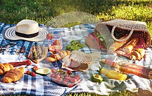 Summer picnic in the park on the grass. Wine, fruit and croissants