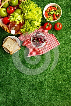 Summer picnic setting. Basket with food on red cloth, top view