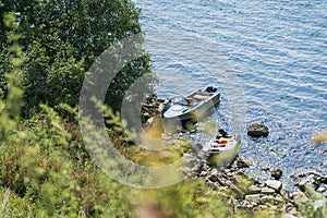 Summer picturesque sunny day, boats on the lake, view from the hill through wild green grass. Natural background