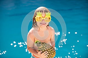 Summer pineapple fruit. Happy child having fun at swimming pool on sunny day. Kids summer holidays and vacation concept.