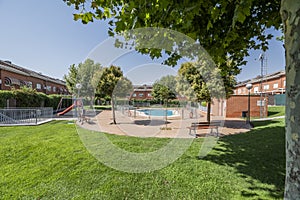 A summer pool in an urbanization with playgrounds, lots of grass and leafy trees